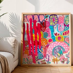 Puede incluir: Una pieza de arte mural cuadrada enmarcada que presenta una composición abstracta vibrante con trazos de pintura rosa brillante, turquesa, amarillo y rojo. El diseño incluye corazones dibujados a mano, un signo de paz, una cara sonriente con ojos en X y la palabra LOVE.