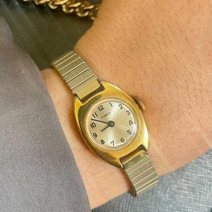 ヴィンテージ クラシック 1970年代 機械式 巻き上げ式 ゴールドトーン ラウンドダイヤル ステンレススチール 伸縮性ストラップ レディース ドレス デイリー 腕時計 タイメックス製