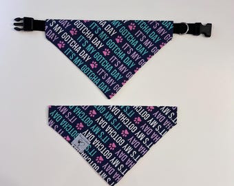 May include: Two dog bandanas with a navy blue background and a repeating pattern of pink and teal paw prints and the text "It's my Gotcha Day".