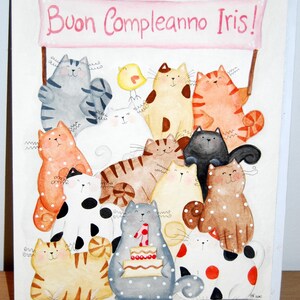 Puede incluir: Una ilustración de acuarela de una tarjeta de cumpleaños con una pancarta rosa con el texto "Buon Compleanno Iris!" y un grupo de gatos con lunares y rayas.