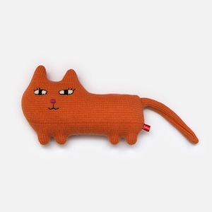 May include: Orange knitted cat plush toy with embroidered eyes, nose, and mouth. The toy has a long tail and small feet.