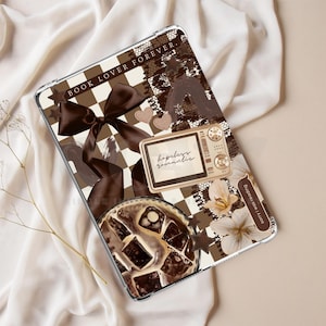 May include: A tablet case with a brown and white chequered design, adorned with a bow, hearts, and a vintage television illustration. The text "BOOK LOVER FOREVER" is displayed on the case.