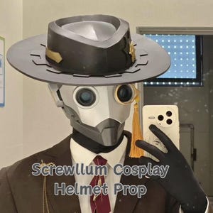 May include: A steampunk-inspired cosplay helmet prop with a silver and black design. The helmet has a wide-brimmed hat, a metallic face mask, and round, blue-tinted lenses. The text "Screwllum Cosplay Helmet Prop" is visible. The person is wearing a brown suit with a burgundy tie.