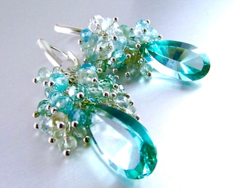 May include: A pair of silver dangle earrings featuring teardrop-shaped blue crystals and clusters of smaller blue and white crystals.