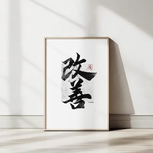 以下が含まれることがあります： 黒インクの日本の書道が特徴の額入りアートプリント。アートワークは、白い背景に文字を形成する大胆な筆致を示しています。小さな赤い印鑑が見えます。フレームは明るい木の色です。