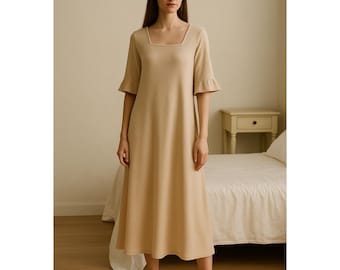 May include: A beige nightdress with a square neckline and ruffled sleeves, reaching to the knees. The soft fabric dress is worn with matching slippers. The background features a bed and a small bedside table.