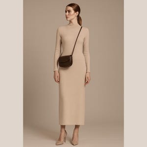 May include: A woman in a long, beige, fitted dress with long sleeves and a high neckline. A small, dark brown leather crossbody bag is worn over the shoulder. The woman is also wearing beige high heels.