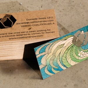 May include: A stack of brown business cards with a logo of two overlapping hexagons. The text on the card reads "Danielle Rees, CFO, danielle@coalitionsnow.com, 1844GO-COALITION ext. 4, We're the ones we've been waiting for. Skis and boards designed by women, for women: www.coalitionsnow.com".