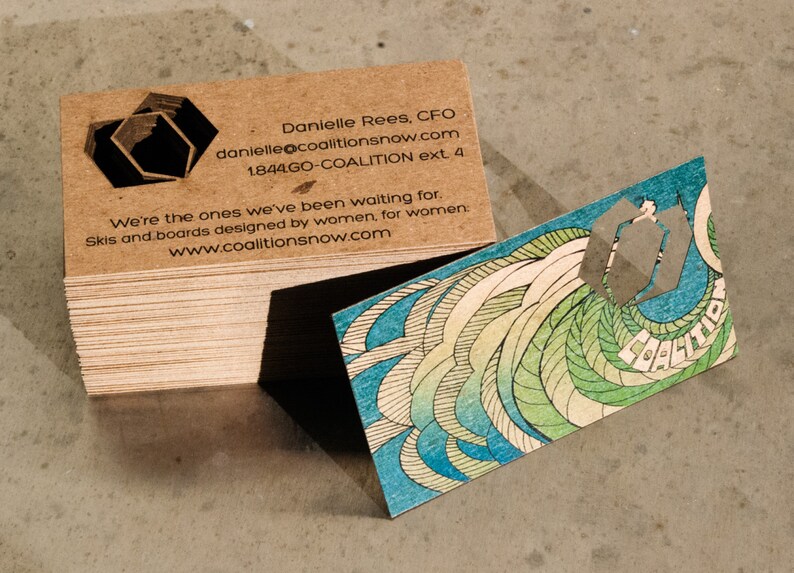 May include: A stack of brown business cards with a logo of two overlapping hexagons. The text on the card reads "Danielle Rees, CFO, danielle@coalitionsnow.com, 1844GO-COALITION ext. 4, We're the ones we've been waiting for. Skis and boards designed by women, for women: www.coalitionsnow.com".