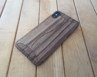 May include: A brown wood phone case with a wood grain pattern. The case has a raised edge around the camera lens.