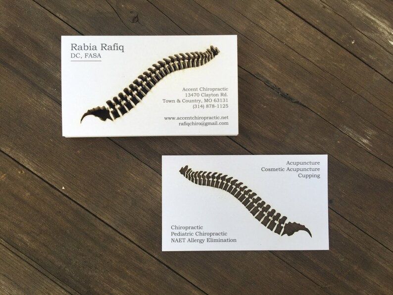 May include: Two white business cards with a black silhouette of a spine. The top card has the text "Rabia Rafiq, DC, FASA, Accent Chiropractic, 13470 Clayton Rd., Town & Country, MO 63131, (314) 878-1125, www.accentchiropractic.net, rafiqchiro@gmail.com". The bottom card has the text "Chiropractic, Pediatric Chiropractic, NAET Allergy Elimination, Acupuncture, Cosmetic Acupuncture, Cupping".