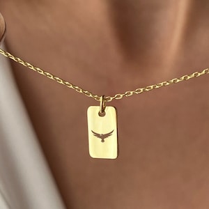 Peut inclure: Un collier en chaîne dorée avec un petit pendentif rectangulaire orné d'un motif découpé d'un oiseau en vol.