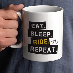 May include: White ceramic mug with black text that reads "EAT. SLEEP. RIDE. REPEAT." with a small black bicycle icon next to the word "RIDE."