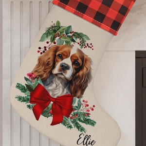 May include: A Christmas stocking with a Cavalier King Charles Spaniel portrait, a red bow, and the name "Ellie." The top is red and black buffalo plaid. A red and white swirled lollipop and gifts are visible.