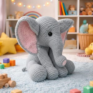May include: A gray crocheted elephant with large ears lined in pink. The elephant has black eyes and is sitting on a light blue rug. The background includes a rainbow and toys, suggesting a nursery or playroom setting.