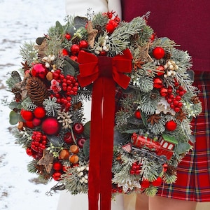 Pode incluir: Uma coroa de Natal festiva com bagas vermelhas, ornamentos e um laço de veludo. A coroa é decorada com pinhas, vegetação e um comboio em miniatura. Uma decoração de férias vibrante.
