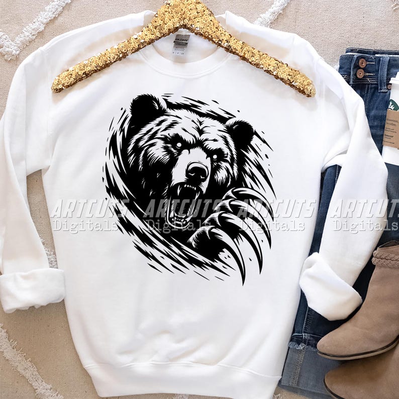 Puede incluir: Una sudadera blanca con un gr&aacute;fico en blanco y negro de la cara de un oso con sus garras a la vista.