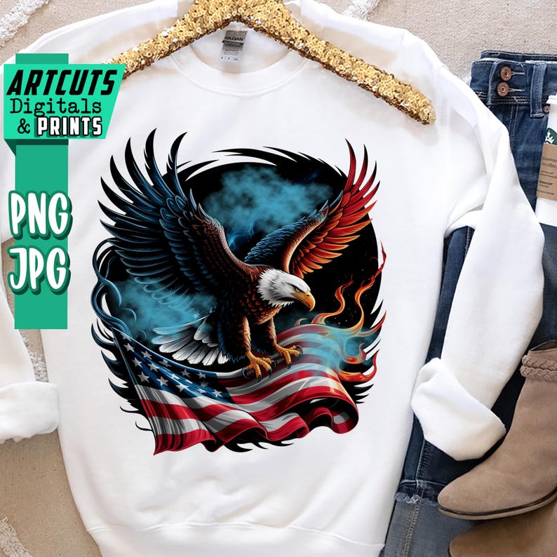 May include: White sweatshirt featuring a detailed graphic of an American bald eagle with outstretched wings, set against a backdrop of the American flag and blue smoke. The design includes the text "ARTCUTS Digitals & Prints" and "PNG JPG".