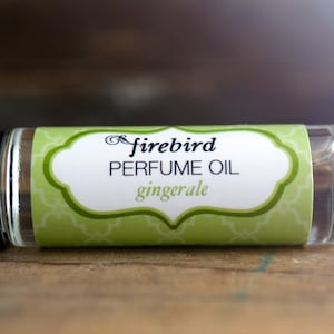Puede incluir: Un frasco de vidrio transparente con un rodillo y una etiqueta verde y blanca que dice "firebird PERFUME OIL gingerale".
