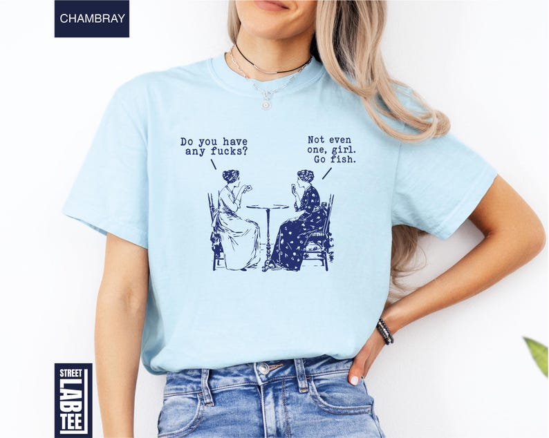 May include: Light blue t-shirt with a navy blue graphic of two women seated at a table, with the text "Do you have any fucks?" and "Not even one, girl. Go fish."