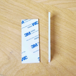 May include: Two white strips of 3M double-coated tissue tape. The tape is labeled with the product number 9448A and the words "Double Coated Tissue Tape".