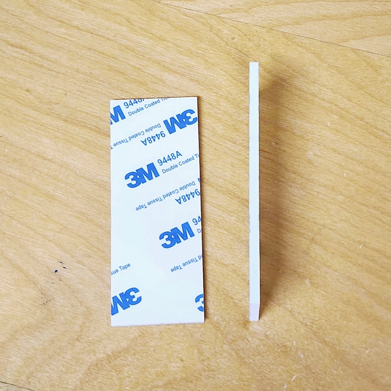 May include: Two white strips of 3M double-coated tissue tape. The tape is labeled with the product number 9448A and the words "Double Coated Tissue Tape".