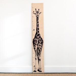 May include: A wooden growth chart featuring a black and white giraffe illustration. The chart has numbers 2, 4, and 5 printed on it.