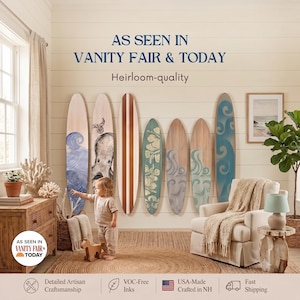 May include: Seven decorative wooden surfboards mounted on a wall, featuring various designs including blue waves, an octopus illustration, and floral patterns. The text reads AS SEEN IN VANITY FAIR & TODAY and Heirloom-quality.