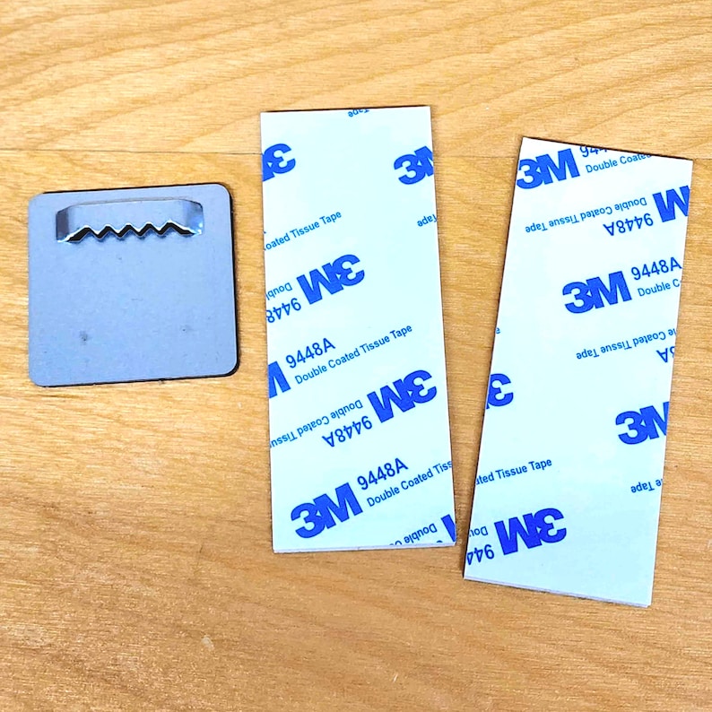 May include: Three white adhesive squares with blue 3M branding and the text "9448A Double Coated Tissue Tape".