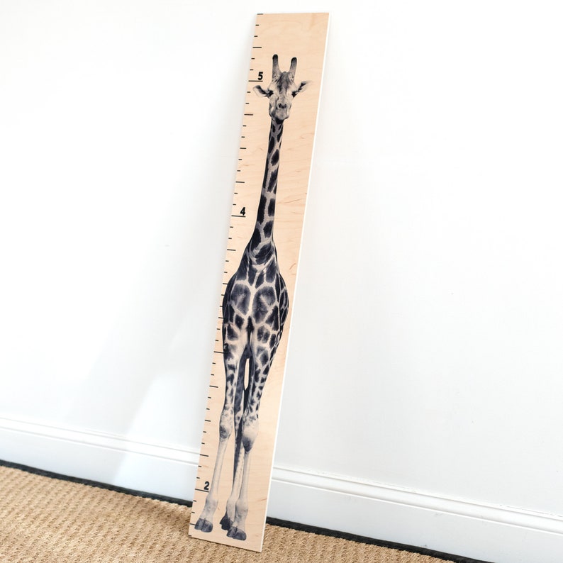 May include: A wooden growth chart featuring a black and white giraffe illustration. The chart has numbers from 2 to 5 printed on it.