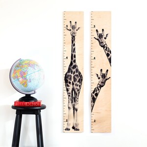 May include: Two wooden giraffe growth charts with black and white giraffe illustrations. The charts are marked with numbers from 2 to 5.