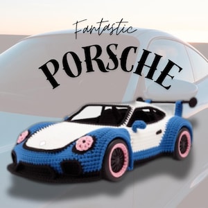 Pode incluir: Um carro de brinquedo de crochê em azul, branco e preto, com detalhes em rosa nas rodas e na frente. O texto "Fantastic PORSCHE" é exibido acima do carro.