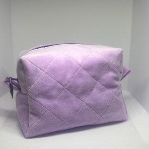 May include: A lavender quilted velvet cosmetic bag with a zipper closure.