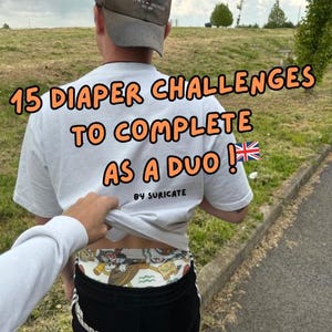 以下が含まれることがあります： 「15 Diaper Challenges To Complete As A Duo!」という文字と、漫画のキャラクターが描かれたおむつをつけた白いTシャツを着た人。Tシャツには「By Suriacate」という文字も書かれている。