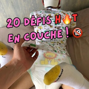 Peut inclure: Une personne portant un t-shirt blanc avec un imprimé d'animaux de dessin animé et une couche avec un imprimé de lion de dessin animé. Le t-shirt porte le texte "20 défis hot en couche!" et "by: suricate". Il y a un emoji de flamme rouge et un cercle rouge avec un numéro 18 blanc à l'intérieur.