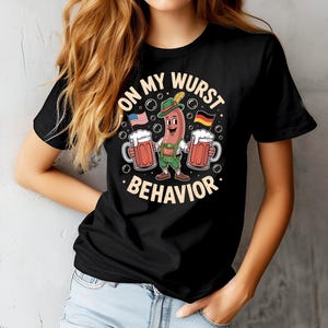 May include: Black t-shirt with a cartoon sausage character holding two mugs of beer, American and German flags, and the text "ON MY WURST BEHAVIOR". The sausage wears a traditional hat and lederhosen.
