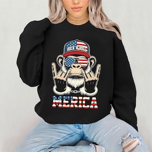 May include: Black sweatshirt featuring a graphic of a monkey wearing sunglasses with the American flag design and a baseball cap with the text "Rock 'N' Roll". The word "MERICA" is displayed in red and white block letters.