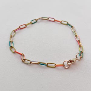 May include: A gold-toned chain bracelet with colorful enamel-filled links. The bracelet features a lobster clasp closure. The enamel colors include red, orange, yellow, green, and blue. The bracelet is displayed on a white background.
