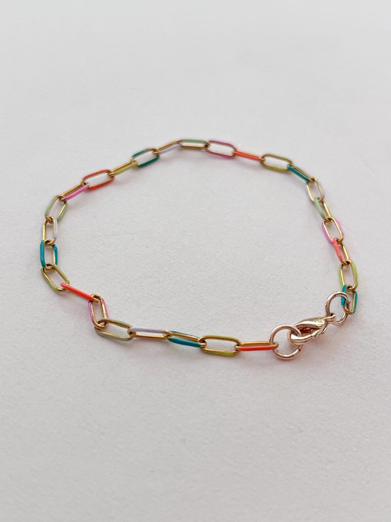 May include: A gold-toned chain bracelet with colorful enamel-filled links. The bracelet features a lobster clasp closure. The enamel colors include red, orange, yellow, green, and blue. The bracelet is displayed on a white background.