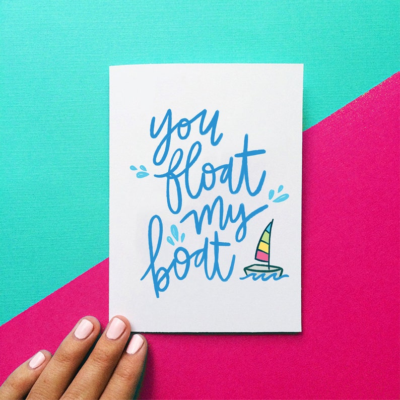 May include: A white card with blue lettering that says "you float my boat" with a small sailboat illustration in the bottom right corner.