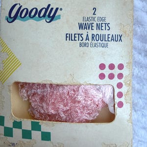 May include: A package of two Goody elastic edge wave nets featuring a light pink mesh material visible through a rectangular cutout. The beige cardboard packaging displays the brand name, product text, and decorative green and pink geometric shapes.