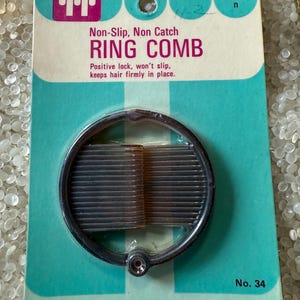 May include: A vintage "Tip-Top" ring comb on a teal and white card. The card reads "Non-Slip, Non Catch RING COMB" and "Positive lock, won't slip, keeps hair firmly in place." The comb is brown and circular.