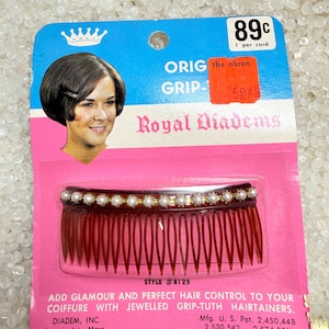 May include: Vintage Royal Diadems hair comb on a pink and blue card. The dark red comb has a row of faux pearls and gold-tone accents. The card features a woman's image and text: "ADD GLAMOUR AND PERFECT HAIR CONTROL TO YOUR COIFFURE WITH JEWELLED GRIP-TUTH HAIRTAINERS."