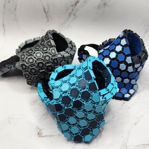 May include: Three face masks made of interlocking hexagonal plastic pieces. The masks are in shades of blue and gray.