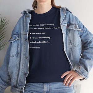 Peut inclure: Un t-shirt bleu marine avec du texte blanc qui dit "brain.exe has stopped working". Le texte comprend des options comme "Give up and rest" et "Hit head on something". La personne porte une veste en jean.