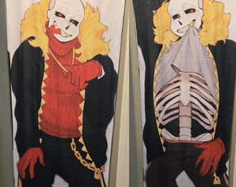 Op de afbeelding: Twee lange, witte kussenslopen met een stripfiguur met een schedelachtig gezicht, rode ogen en een rood-zwarte outfit. Eén hoes toont het hele lichaam, de andere het skelet.