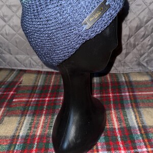 Peut inclure: Un bonnet en tricot bleu et vert avec une &eacute;tiquette noire indiquant "Handmade with Love".