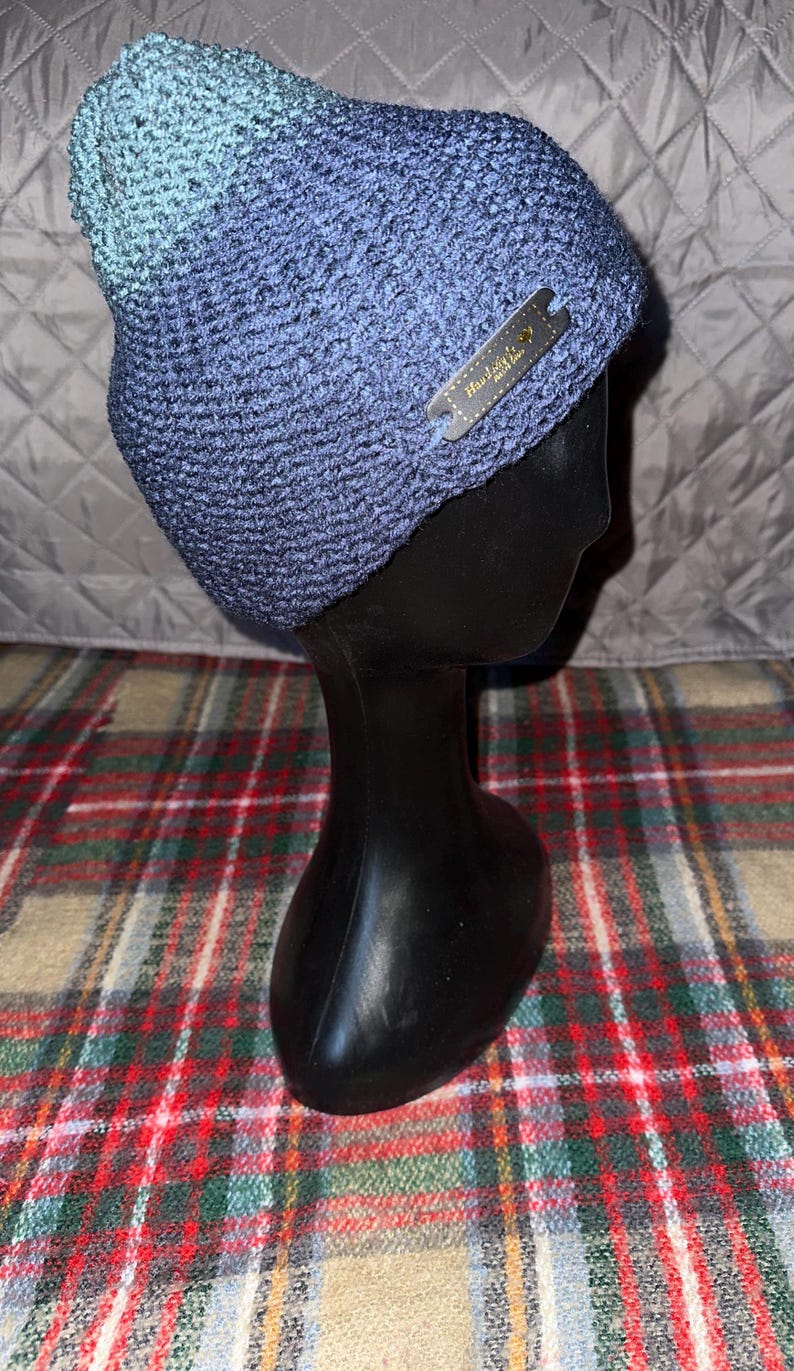 Peut inclure: Un bonnet en tricot bleu et vert avec une &eacute;tiquette noire indiquant "Handmade with Love".