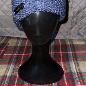 Peut inclure: Un bonnet en tricot bleu et vert avec une petite &eacute;tiquette noire indiquant "Oakland, CA".