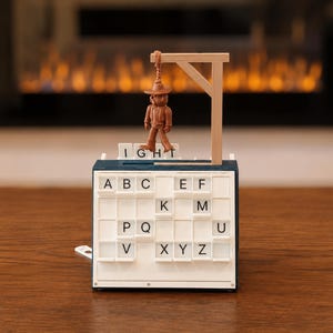 May include: A white and blue plastic word game board featuring a grid of letter tiles including A, B, C, E, F, K, M, P, Q, U, V, X, Y, and Z. A small brown plastic figure wearing a hat hangs from a light-colored wooden gallows structure.